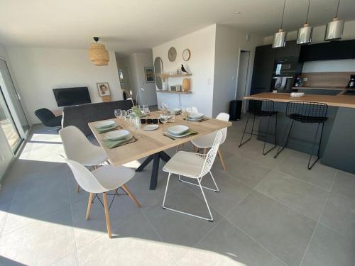 een eetkamer en een woonkamer met een tafel en stoelen bij Maison neuve vue panoramique sur la mer 6 pers à Crozon in Crozon