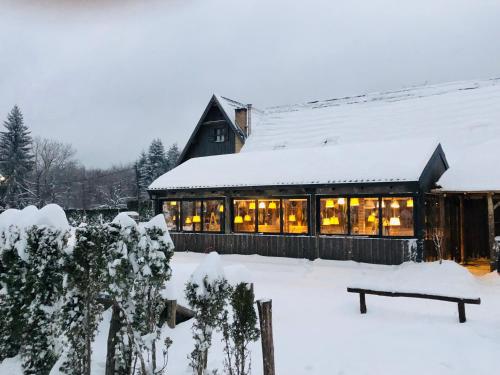 een huis in de sneeuw met lichten aan bij Ethno Houses Plitvice Lakes Hotel in Plitvica selo