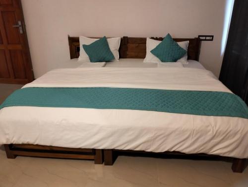 een groot bed met groene en witte lakens en kussens bij Devi Kripa Residency in Varkala