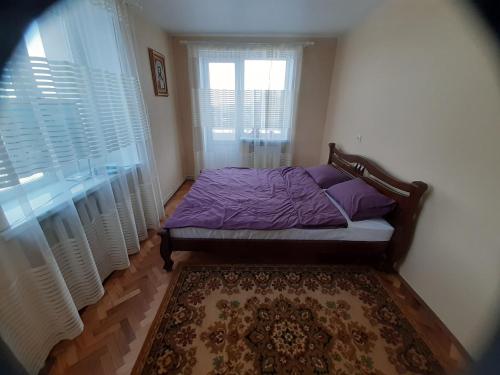 Un dormitorio con una cama con almohadas moradas y una ventana en Квартира в Коломиї, en Kolomyia