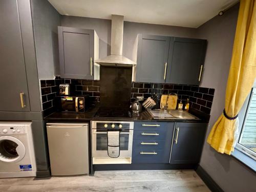 uma cozinha com armários azuis e um forno com placa de fogão em Stylish Studio Flat With Private Patio em Bournemouth