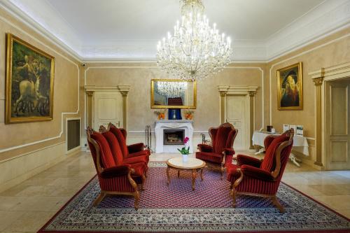 uma sala de estar com cadeiras vermelhas e um lustre em Hotel Château Cihelny em Karlovy Vary