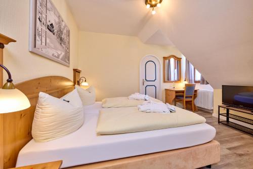 um quarto com uma cama, uma mesa e uma televisão em Hotel Vier Jahreszeiten em Garmisch-Partenkirchen