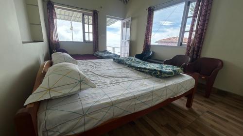 a bedroom with a bed with two windows at AG Cottage Vattakanal in Kodaikānāl