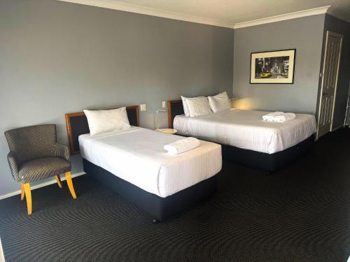 um quarto de hotel com duas camas e uma cadeira em Old Maitland Inn em Maitland