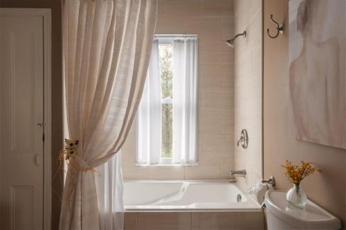 a bathroom with a tub and a toilet and a window at Auberge Old Chelsea in Chelsea