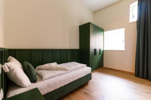 una camera con letto e testiera verde di Casa Fellin Guesthouse a Vipiteno