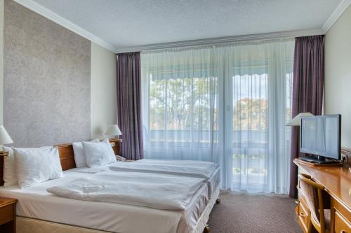 a hotel room with a bed and a television at Ensana Thermal Hévíz in Hévíz