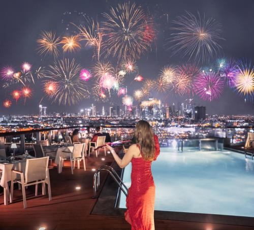 una donna sul bordo di un tetto con fuochi d'artificio di Golden Sands Boutique Hotel-Dubai Creek a Dubai