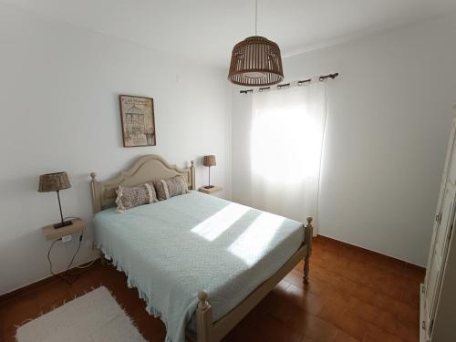 una camera bianca con un letto e una finestra di Casa Pereira a Vila Nova de Milfontes