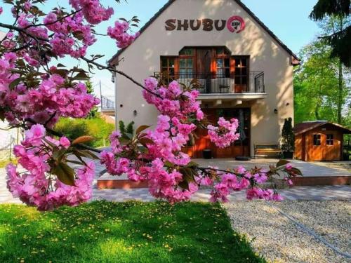 uma casa com flores cor-de-rosa em frente em Shubu Zen Vendégház em Szilvásvárad