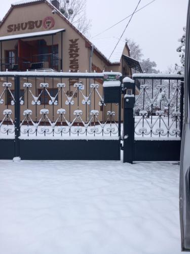 um portão com neve em frente a um edifício em Shubu Zen Vendégház em Szilvásvárad