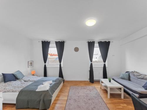 een witte slaapkamer met een bed en een bank bij Stockerau Comfort Studio 1 BR for 2 in Stockerau