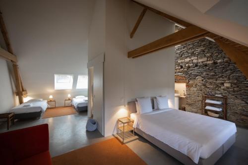 a bedroom with two beds and a stone wall at Château du Pont d'Oye in Habay-la-Neuve