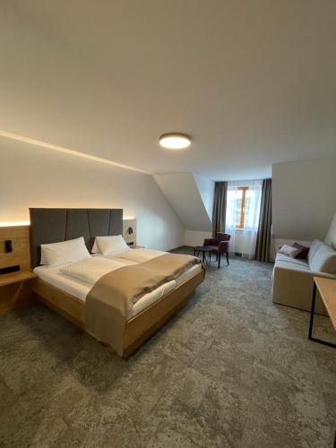 - une chambre avec un grand lit et un canapé dans l'établissement Hotel Goldener Engel, à Ihringen