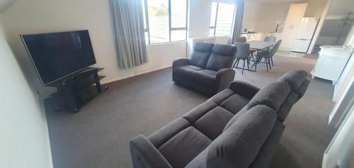 een woonkamer met een bank en een televisie bij The Haven Newmarket Suites in Auckland