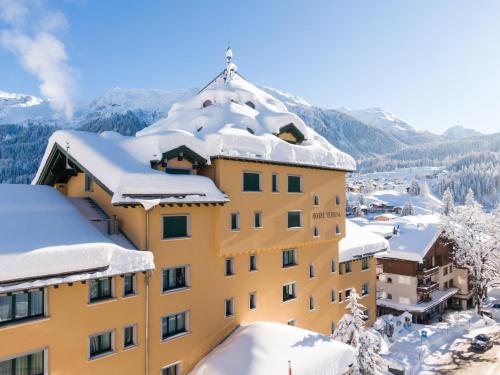 un edificio ricoperto di neve con montagne sullo sfondo di Hotel Vereina a Klosters