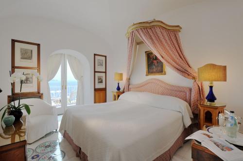 ein Schlafzimmer mit einem weißen Bett und einem Fenster in der Unterkunft Le Sirenuse in Positano