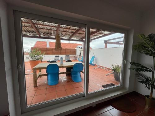 a sliding glass door with a table and chairs on a patio at Penthouse Alentejana in Vila Nova de Milfontes