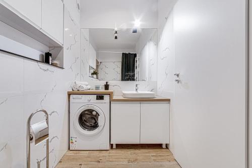 een witte badkamer met een wasmachine en een wastafel bij ARI - AFI Mall Luxurious Apartments with Free Parking in Arad