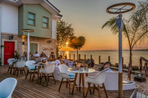 un restaurant avec des tables et des chaises sur une terrasse au bord de l'eau dans l'établissement Carpe Diem Boutique Hotel - Adults Only, à Sidé