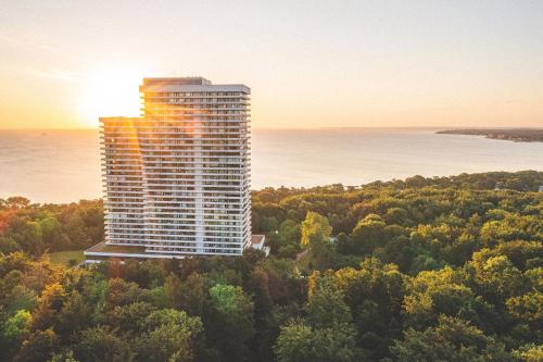 een hoog gebouw midden in een bos met de zonsondergang bij PLAZA Premium Timmendorfer Strand in Timmendorfer Strand