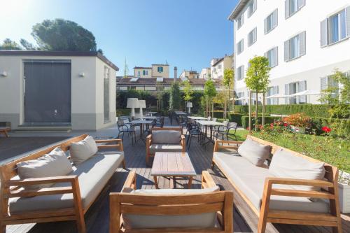 un patio con sillas, mesas y una pantalla en Palazzo Castri 1874 Hotel & Spa, en Florencia