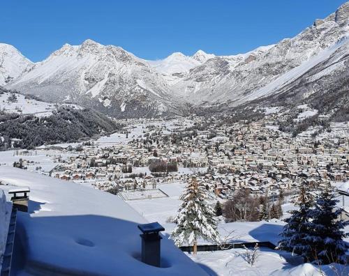 una città nella neve con montagne sullo sfondo di Casa Grafa Bormio a Valdisotto