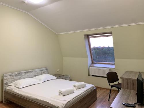 um quarto com uma cama, uma janela e uma cadeira em Budget Hotel Ekotel em Lviv