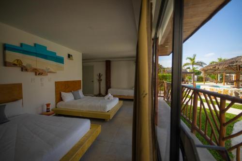 a hotel room with two beds and a balcony at Kabañas Ojo de Agua in Puerto Morelos