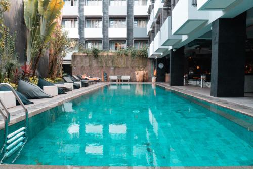 a swimming pool with blue water in a building at IKOSHAROLD Suites Seminyak in Seminyak