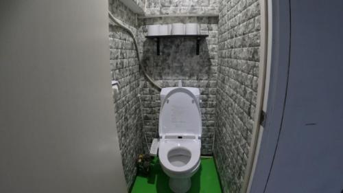 ein kleines Bad mit einem WC in einer Ziegelwand in der Unterkunft Sophiearth Apartment in Tokio