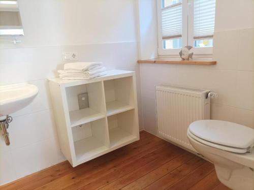 een witte badkamer met een toilet en een wastafel bij Emely Ferienwohnung in Röbel