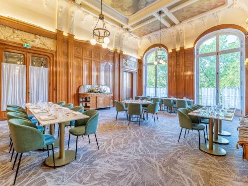 un comedor con mesas, sillas y ventanas en Mercure Lyon Centre Château Perrache, en Lyon