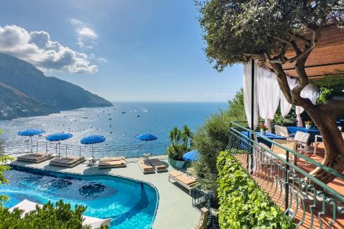 - une piscine avec des chaises et des parasols à côté de l'océan dans l'établissement Hotel Le Agavi, à Positano