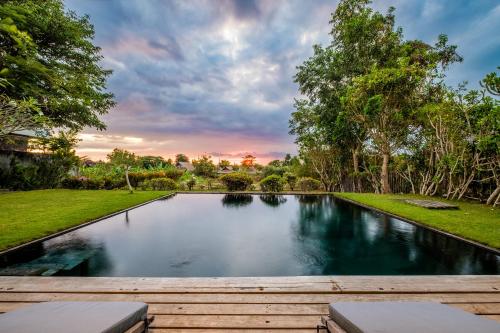 - une piscine dans une cour avec une terrasse en bois dans l'établissement Beachfront Villa Nakar Two, à Jimbaran