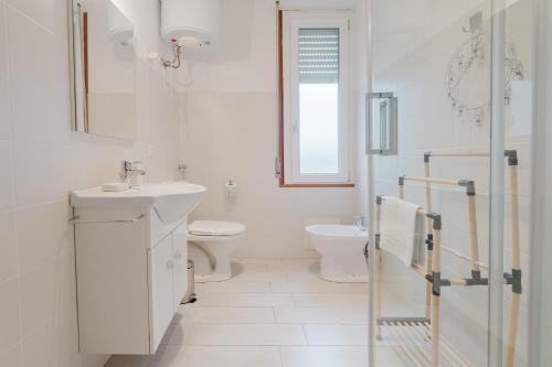 ein weißes Bad mit einem Waschbecken und einem WC in der Unterkunft B&B La finestra sul porto in Porto Torres