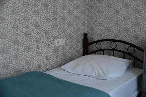 a bed with a white pillow and a wall at Babulya House in Gyumri