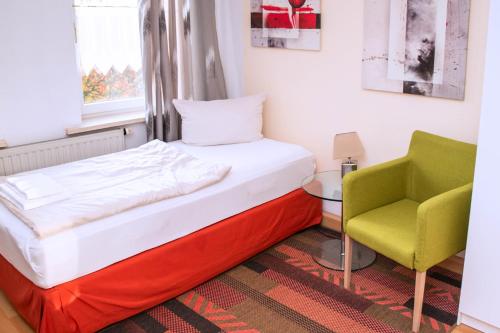 a bed and a chair in a room at Rothenberger Plauen in Plauen