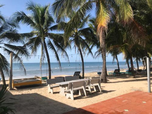 un tavolo e sedie su una spiaggia con palme di Nhat Quang Bungalow a Mui Ne