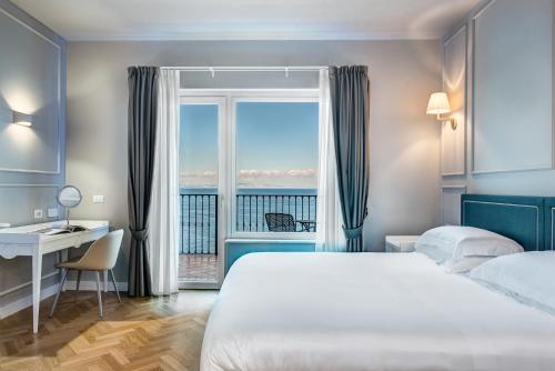 een slaapkamer met een bed, een bureau en een raam bij Imperial Hotel Tramontano in Sorrento