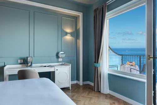 een slaapkamer met een bed, een bureau en een balkon bij Imperial Hotel Tramontano in Sorrento