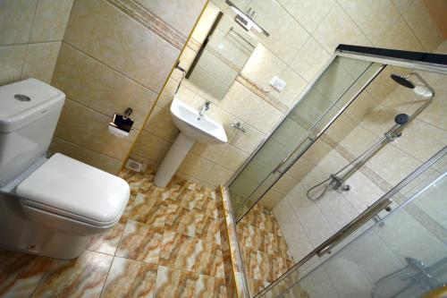 ein Bad mit einer Dusche, einem WC und einem Waschbecken in der Unterkunft Lake View Apartments in Luzira