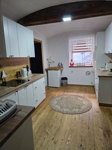 a kitchen with white cabinets and a wooden floor at Natalia in Leoben