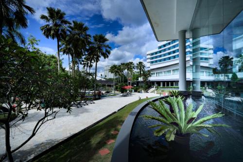 een resort met palmbomen en een gebouw bij Thistle Johor Bahru in Johor Bahru