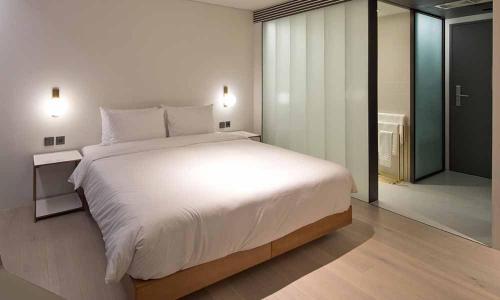 a bedroom with a large white bed and a sliding glass door at Cont Hotel in Busan