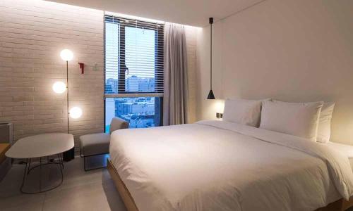 a bedroom with a large white bed and a table at Cont Hotel in Busan