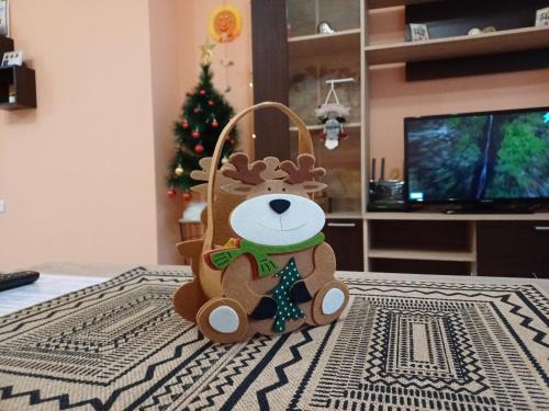 Un ours en peluche assis sur une table avec un arbre de Noël dans l'établissement Sunflower Apartment City Center, à Plovdiv