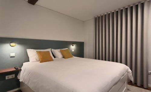 a bedroom with a large white bed and a window at DOMI Suites & Studios in Guimarães