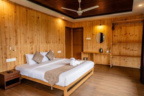 1 dormitorio con 1 cama en una pared de madera en ZACS VALLEY RESORT, Kodaikanal, en Kodaikanal